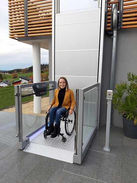 Plateforme élévatrice verticale UnaPorte avec mise en situation d'une femme en fauteuil roulant